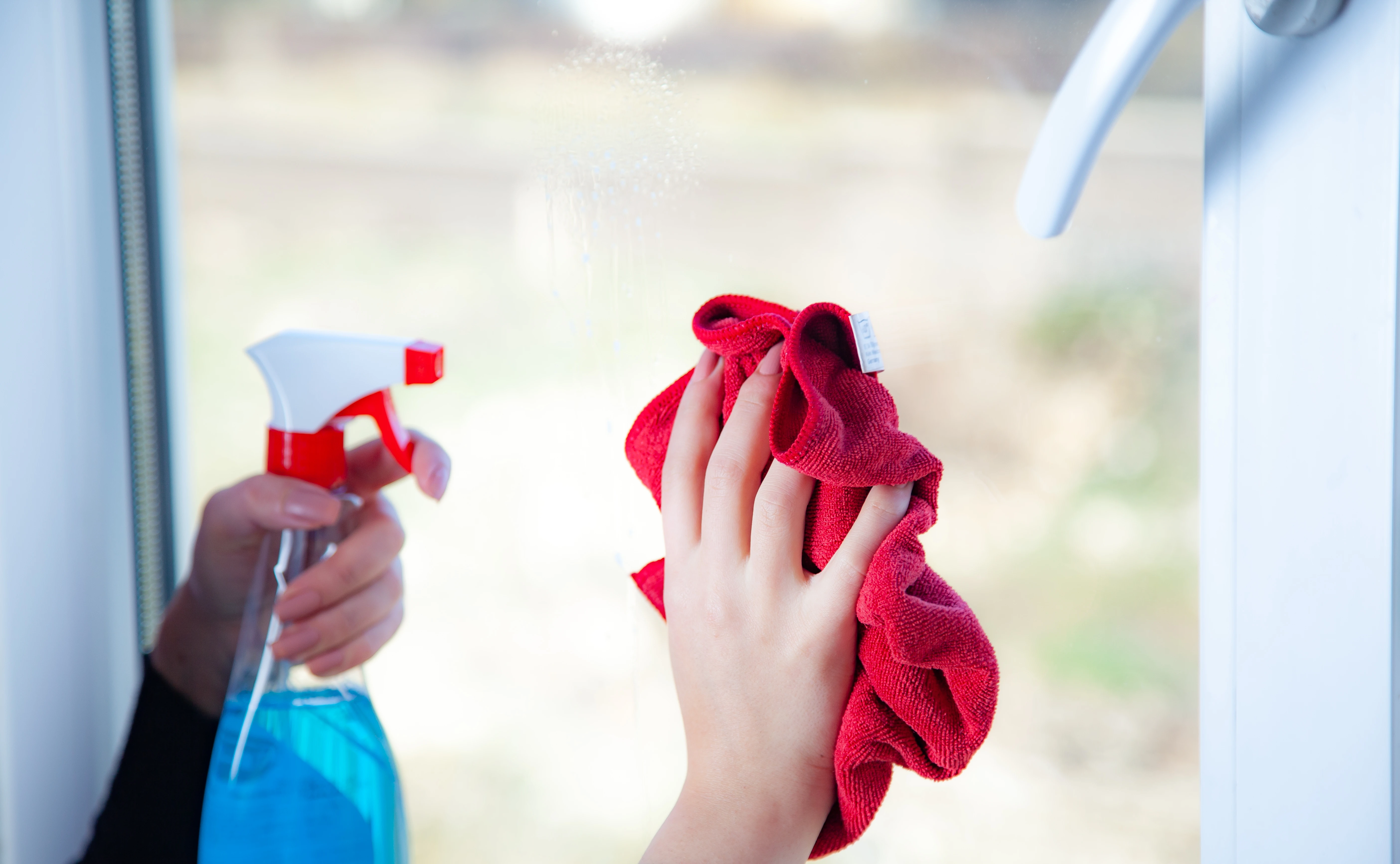 Cleaning in progress: hands with spray bottle and red rag